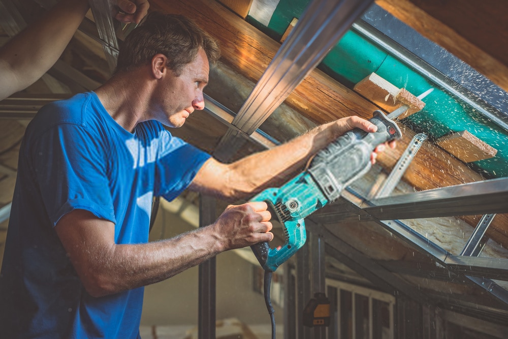 A person is cutting a board of wood with Best reciprocating saw A person is cutting a board of wood with Best reciprocating saw