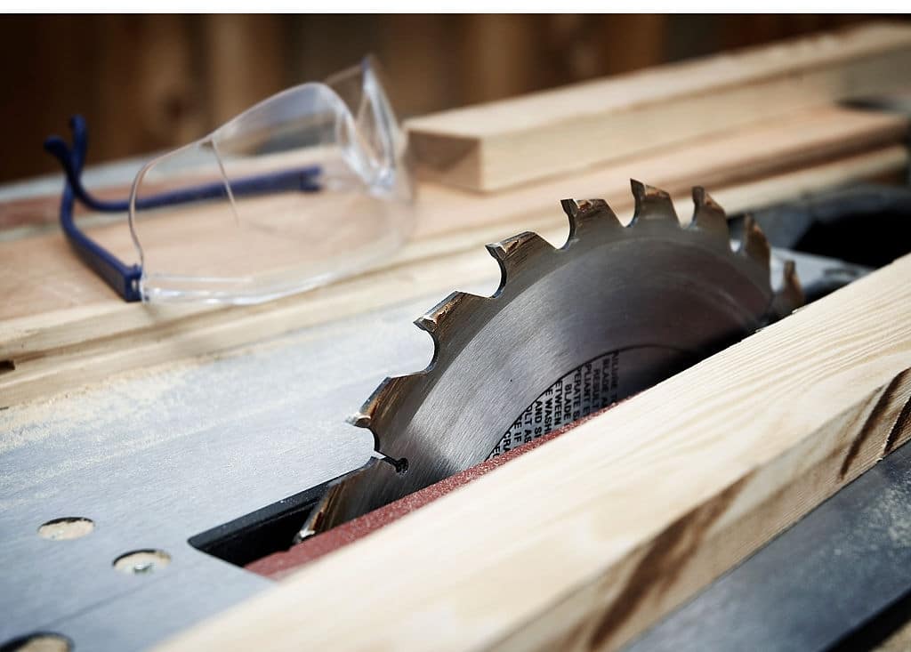 Table saw with pieces of cut wood and safety glasses A table saw with wood and safety goggles