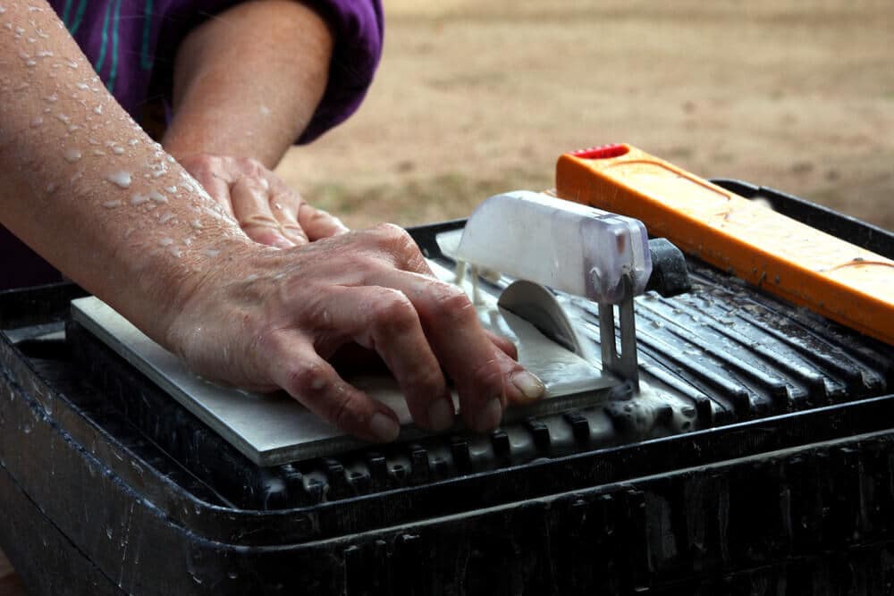 Man holds his hands near a Tile saw without safety Man holds his hands near a Tile saw without safety
