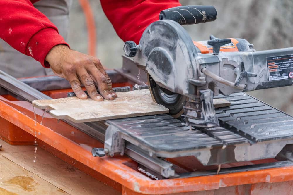 Worker Using Wet Tile Saw to Cut Wall Tile At Construction Site Worker Using Wet Tile Saw to Cut Wall Tile At Construction Site