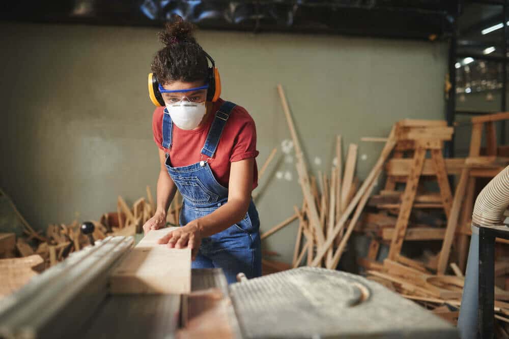 Cuts Professional female carpenter cutting wooden board on table saw