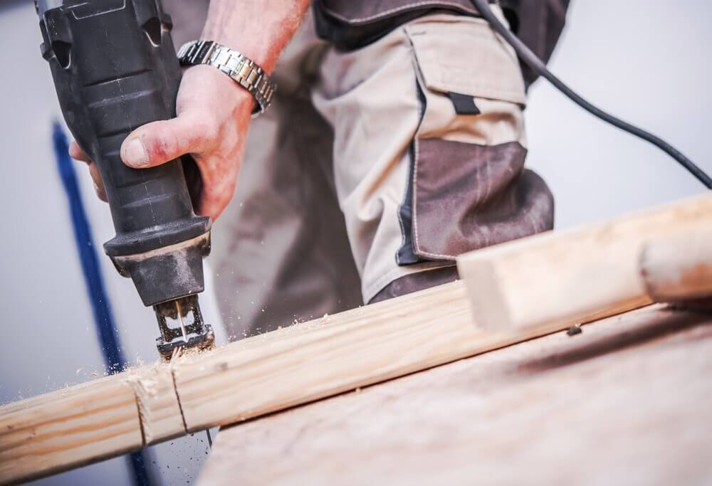 cuts-through-wood Male carpenter cuts wood with reciprocating saw