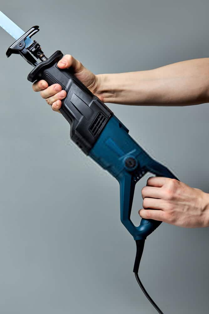 pressing the trigger Male hands pressing the trigger of Reciprocating saw