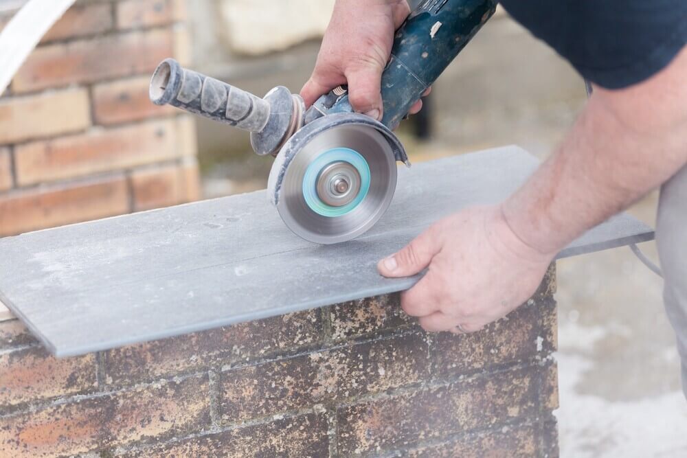 tile-grinder construction worker uses a grinder for cutting a tile